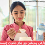 Young sporty woman measuring scoop of whey protein, making replacement food meal after workout